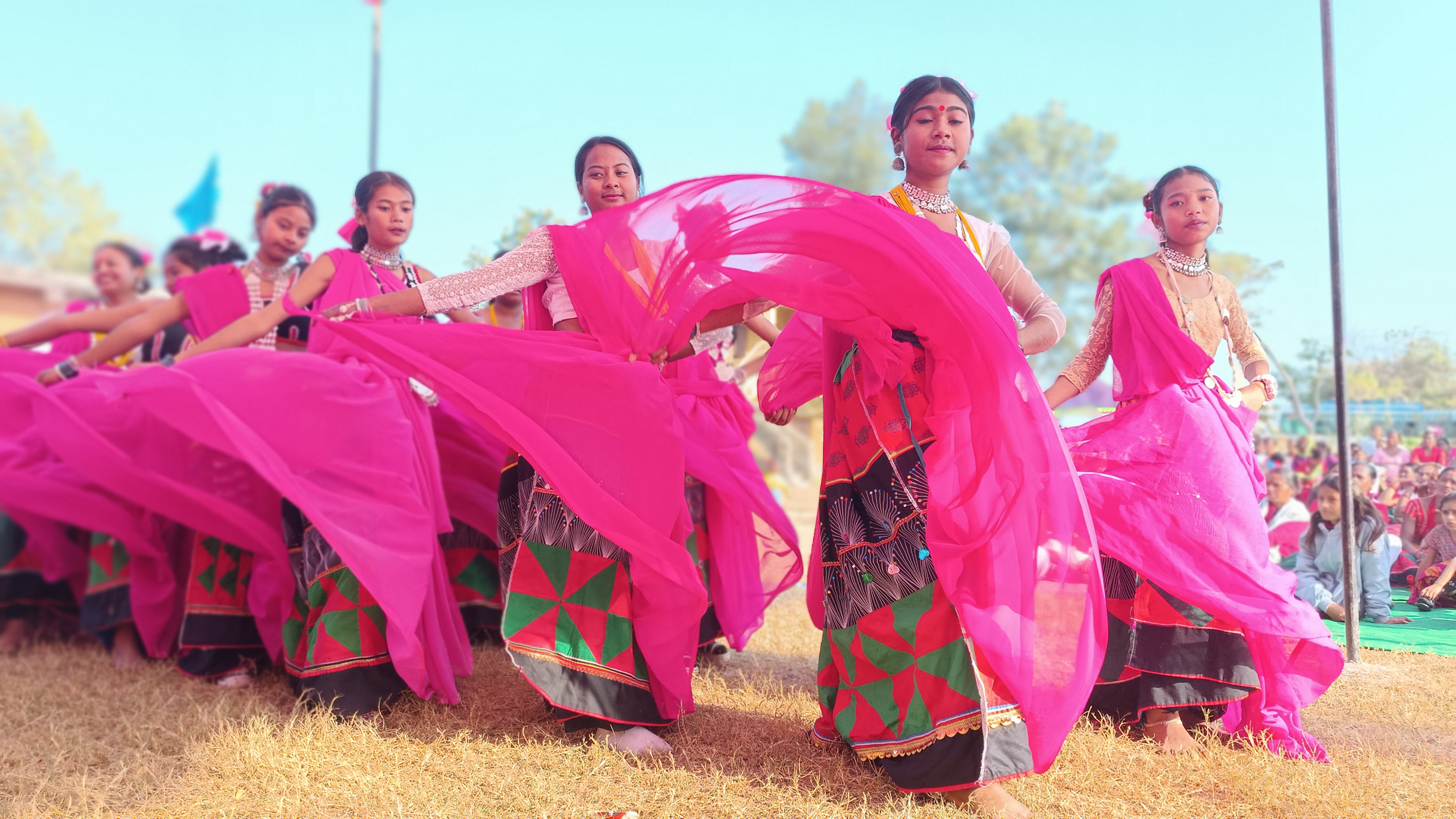 Young girls in pink traditional dress welcoming the team